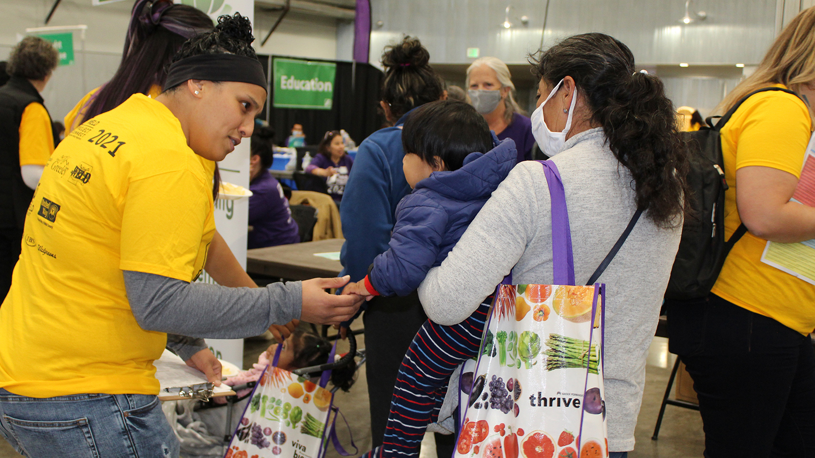 volunteer assisting a mother and her young child at an event